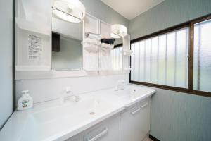 W białej łazience znajduje się umywalka i lustro. w obiekcie Yumeguri no yakata Yoshinozakura - Vacation STAY 83043v w mieście Yufu