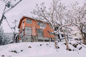 a building is covered in snow in front at Yuzawa Onsen Lodge 1min to LIFT House in Seki