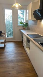 uma cozinha com armários brancos e pisos e janelas em madeira em Jolie appartement proche bords de Loire em Orléans