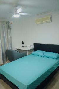 A Spacious Room with Private Toilet في غولد كوست: غرفة نوم بسرير أزرق وطاولة