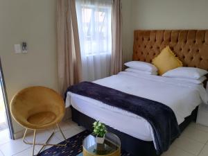 um quarto com uma cama grande e uma cadeira em EMPEROR LODGE AND TOURS em Germiston