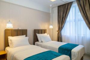 two beds in a hotel room with a window at Moodhukoe in Male City