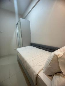 Bett in einem Zimmer mit einer weißen Wand in der Unterkunft Tanglin Orchard Apartment by Kondoku in Lontar