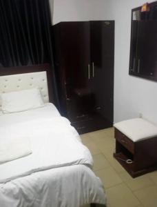 a bedroom with a white bed and a table and window at Dovan Lodge Enugu in Enugu