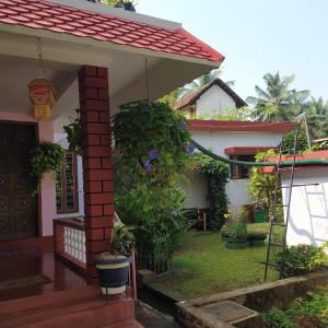 a house with a red roof and a porch at Runnin Airport - Homestay in Gurpur