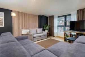 a living room with a couch and a tv at Urban Oasis: Heart of City by Train in Leeds