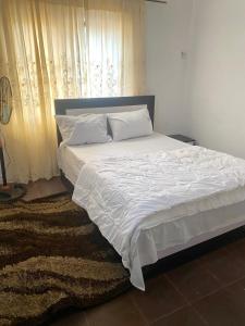 a bedroom with a bed with white sheets and a window at Enugu Apartments in Enugu