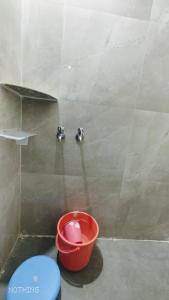 um balde vermelho num chuveiro com um balde em Aadishkti bhakt nivas em Tuljapur