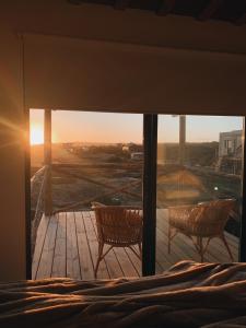 ein Schlafzimmer mit einem Bett und zwei Stühlen auf einer Terrasse in der Unterkunft Casa Franca in José Ignacio