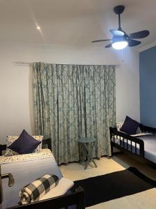 a bedroom with two beds and a ceiling fan at Immaculate Morden Scenic Villa in Ezulwini