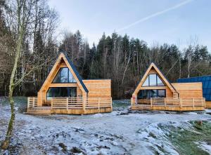 eine Gruppe von drei Blockhäusern im Schnee in der Unterkunft Mountains & Lakes - Chaletdorf in Villach