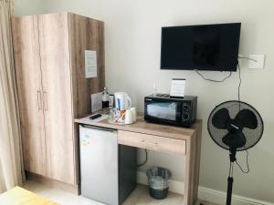 a kitchen with a desk with a microwave and a refrigerator at Hermanus Guest Rooms in Hermanus