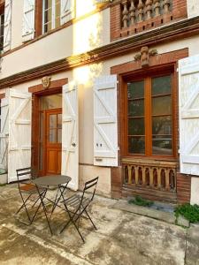 uma mesa e duas cadeiras em frente a um edifício em Cocon cosy dans la ville rose em Toulouse