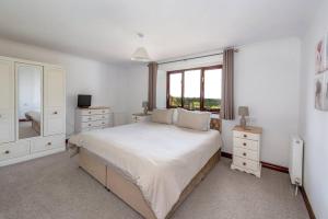 - une chambre blanche avec un grand lit et une fenêtre dans l'établissement Holgates Cottage Countryside Retreat, à Upottery