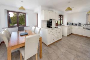 a kitchen with a wooden table and white cabinets at Holgates Cottage Countryside Retreat in Upottery