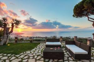 索倫托的住宿－Luxury Villa with breathtaking Seaview, pool, BBQ，一个带沙发和桌子的庭院,享有日落美景