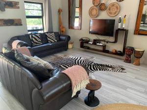 a living room with a leather couch and a zebra rug at Sweni Lodge 91 Mjejane Kruger Park in Hectorspruit