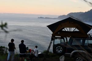 um grupo de pessoas ao redor de um carrinho de golfe com o oceano em Overland Madeira em Santana