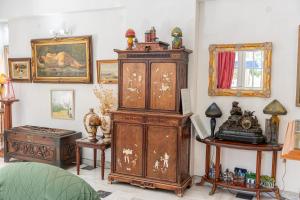 a large wooden cabinet in a room with paintings at Odysseus Palace in Póros Kefalonias