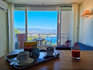 - une table avec deux tasses et un plateau de nourriture dans l'établissement Appartement 3P traversant vue mer et forêt - Les clés de l´Estérel, à Théoule-sur-Mer