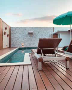 een terras met een stoel en een parasol naast een zwembad bij Casa com piscina climatizada em frente à Praia do Santinho in Florianópolis