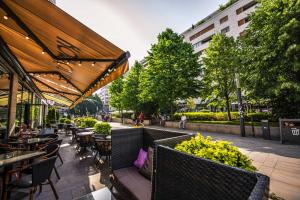 un patio extérieur avec des tables, des chaises et des fleurs dans l'établissement Corvin Promenade Crystal, à Budapest