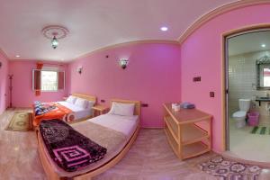 een roze slaapkamer met een bed en een badkamer bij Hotel De La Vallée in Aït Baha