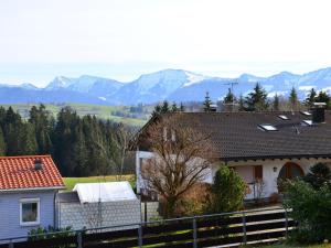 ein Haus mit einem Zaun und Bergen im Hintergrund in der Unterkunft NEU! Ferienwohnung Konz inkl Sauna in Oberreute