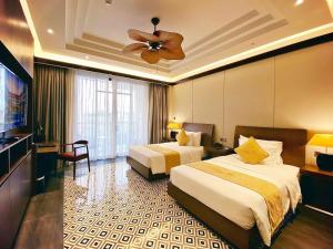 a hotel room with two beds and a ceiling fan at Senna Hue Hotel in Hue