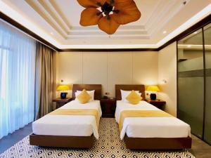 a hotel room with two beds and a ceiling fan at Senna Hue Hotel in Hue