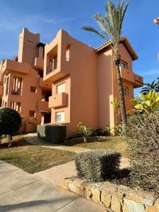 a building with a palm tree in front of it at Lakeview Residence 'Casa Naranjas' Mar Menor Golf and Leisure Resort in Torre-Pacheco