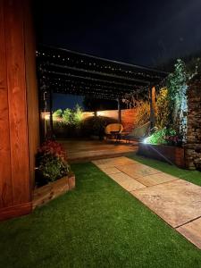 un patio nocturno con banco y luces en The Cottage Hideout, en Upholland