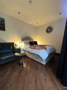 1 dormitorio con cama, sofá y reloj en The Cottage Hideout, en Upholland