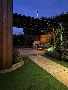 a patio with a bench in a garden at night at The Cottage Hideout in Upholland