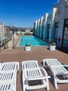 dos bancos blancos sentados junto a una piscina en Depto 2dorm/2baños, estac Viña, en Viña del Mar