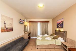 een hotelkamer met een bed en een bank bij Jo An Beach Hotel in Adelianos Kampos