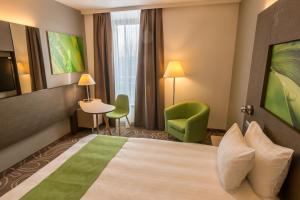 ブダエルシュにあるHoliday Inn Budapest-Budaörs, an IHG Hotelのベッド、テーブル、椅子が備わるホテルルームです。