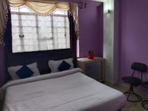 a bedroom with a bed with purple walls and a window at Winnie's Lodge , Shillong in Shillong