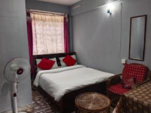 a bedroom with a bed with red pillows and a window at Winnie's Lodge , Shillong in Shillong
