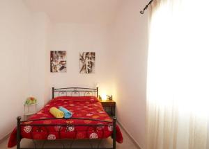 a bedroom with a red bed and a window at Alexandros House in Monolithos