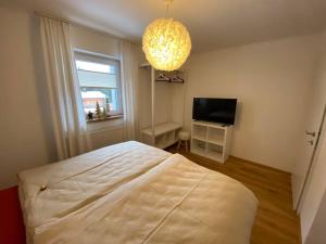 um quarto com uma cama, uma televisão e um lustre em Herzzeit Apartments em Flachau