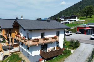 uma casa branca com uma varanda e um parque de estacionamento em Herzzeit Apartments em Flachau