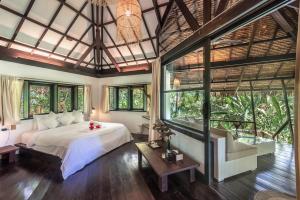 1 dormitorio con 1 cama en una habitación con ventanas en kawayan villa siargao, en General Luna