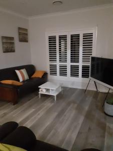 a living room with a couch and a flat screen tv at Adwaga Lodge in Tamborine