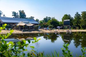 a view of a lake with a building and tents at Glamping Limburg - nabij Nationaal Park Hoge Kempen in Kinrooi