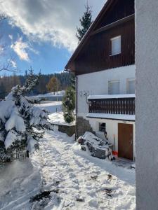 una casa cubierta de nieve con un coche aparcado al lado en Pod Jeleńcem, en Karpacz