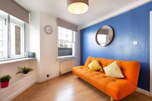 an orange couch in a blue room with a mirror at Apartments are located in the Heart of Shoreditch in London