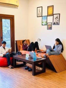 un grupo de personas sentadas en una sala de estar con sus ordenadores portátiles en A Sleepy Fox Hostel, en Nueva Delhi