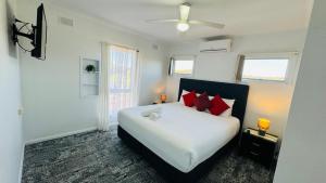 a bedroom with a large white bed with red pillows at Clare Valley Motel in Clare