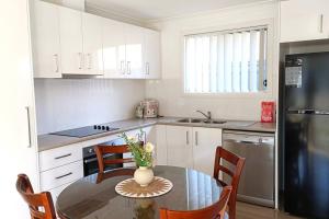 eine Küche mit einem Tisch und Stühlen sowie einem Kühlschrank in der Unterkunft New and Cozy 2 Bedrooms Granny Flat with Aircon & Pool in Baulkham Hills